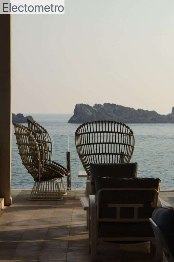 a couple of chairs sitting on top of a patio next to a body of water