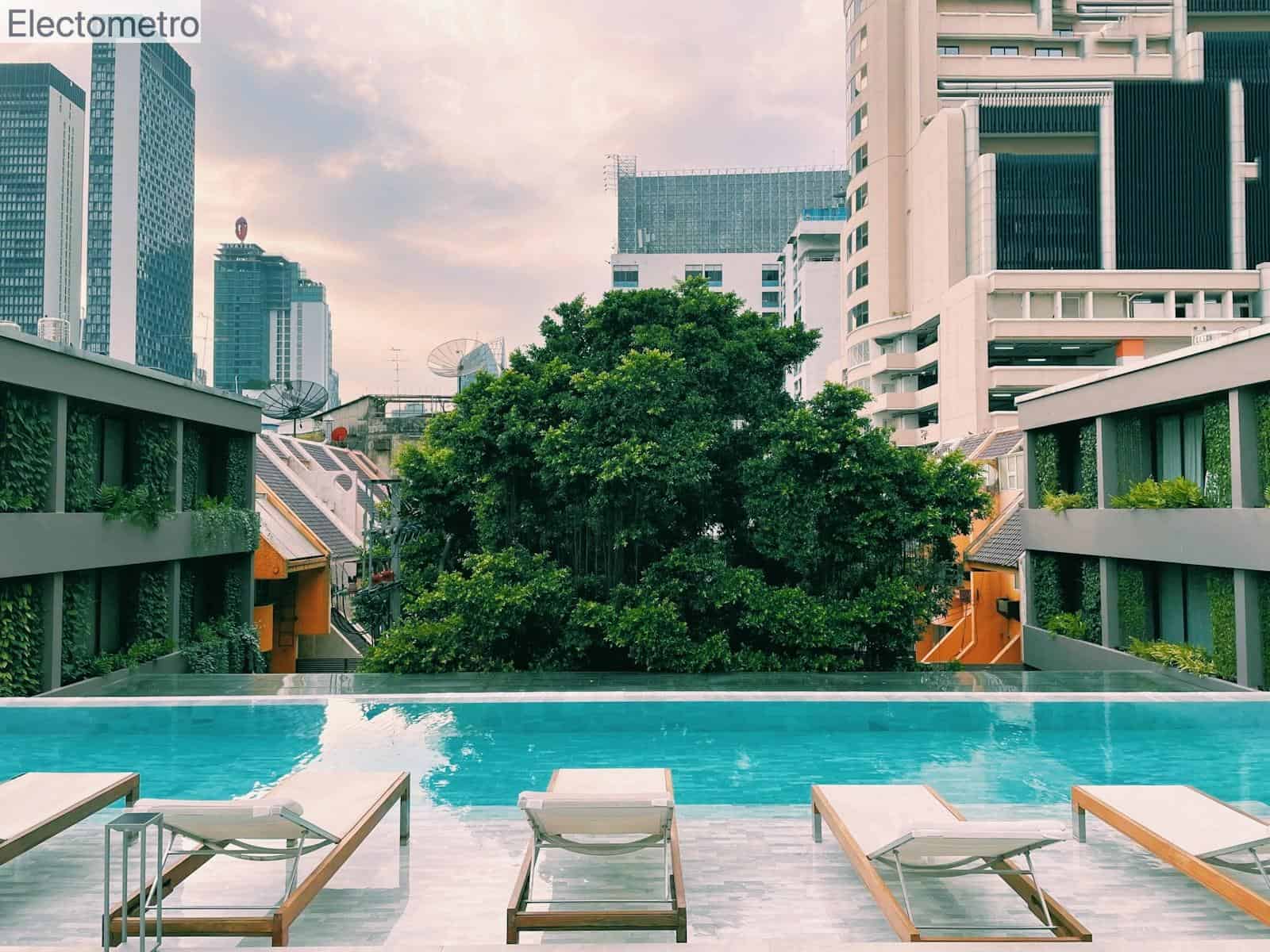 a swimming pool with lounge chairs and trees in the background
